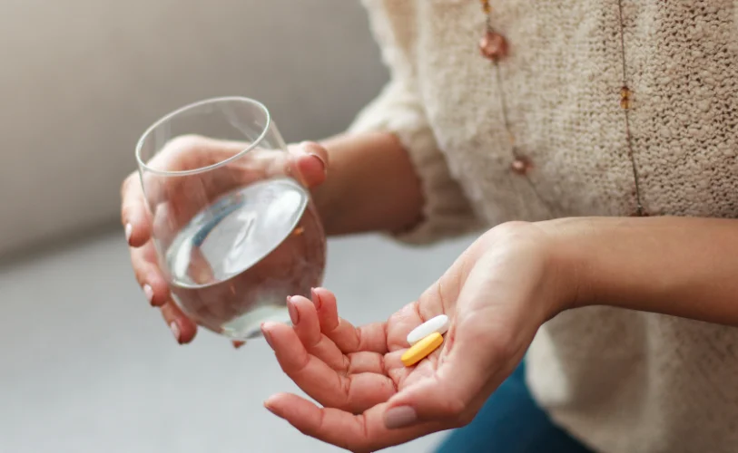 Person holding medication and a glass of water